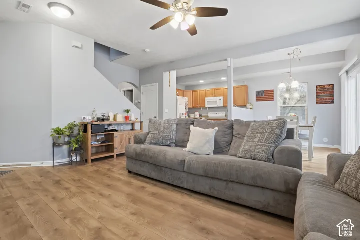 Wood-finish flooring, vaulted ceilings with a center-mounted ceiling fan, and architectural archway detailing