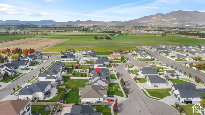 Aerial perspective of suburban neighborhood featuring residential lots, paved streets, manicured lawns, and prominent mountain backdrop