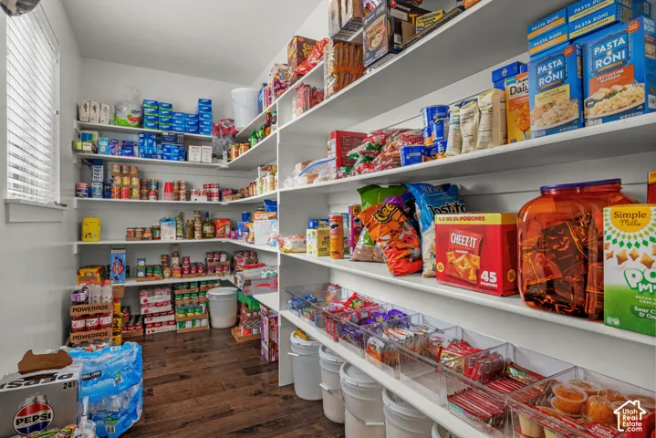 Walk-in pantry featuring white wrap-around shelving, shiplap wall accents, and wood-finish flooring