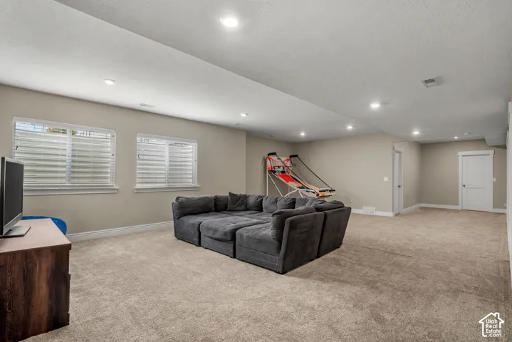 Spacious room featuring neutral carpeting, recessed ceiling lighting, two sets of double-pane windows, and minimalist interior doors