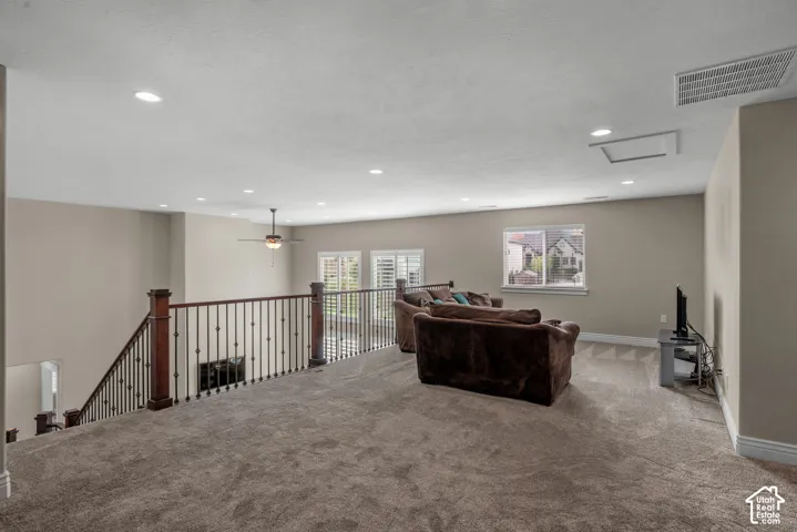 Open-concept mezzanine featuring recessed lighting, carpeted flooring, metal balusters with wooden handrails, and plantation shutters