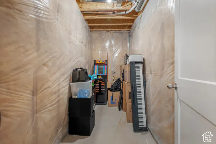 Unfinished storage area featuring exposed wood-joist ceiling, concrete flooring, and plastic-sheathed insulation walls