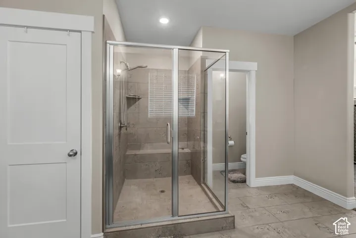 Walk-in shower with a glass enclosure, built-in tile bench, neutral tile surround, and tile flooring