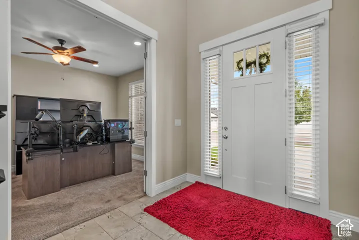 Entryway featuring high ceilings, neutral wall tones, tile flooring, and a white front door with dual sidelights and a glass transom window