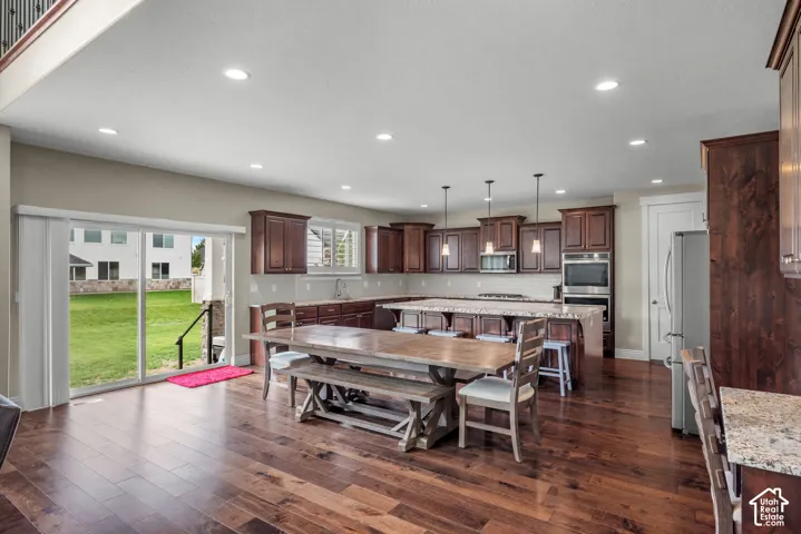 Kitchen featuring dark wood cabinetry, a central island with countertop seating, stone-finish countertops, recessed lighting, and wood-finish flooring