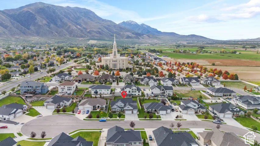 Aerial perspective of residential property featuring a multi-gabled roofline, stone and horizontal siding exterior, and mountain backdrop