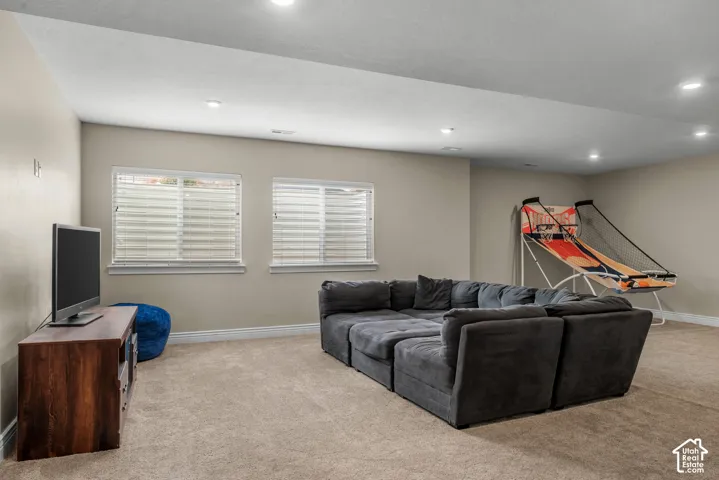 Neutral-toned interior space featuring recessed ceiling lighting, carpeted flooring, and two egress windows with horizontal blinds