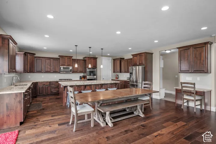 Kitchen featuring dark wood cabinetry, stone countertops, central island, wood-finish flooring, and recessed lighting