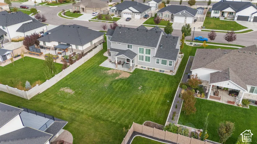 Two-story residential exterior featuring a grey siding finish, an asphalt shingle roof, a covered rear patio, and a fenced-in grassy yard
