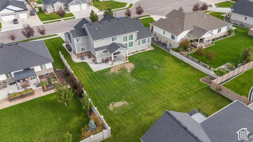 Expansive backyard featuring a concrete patio, perimeter fencing, and a manicured lawn