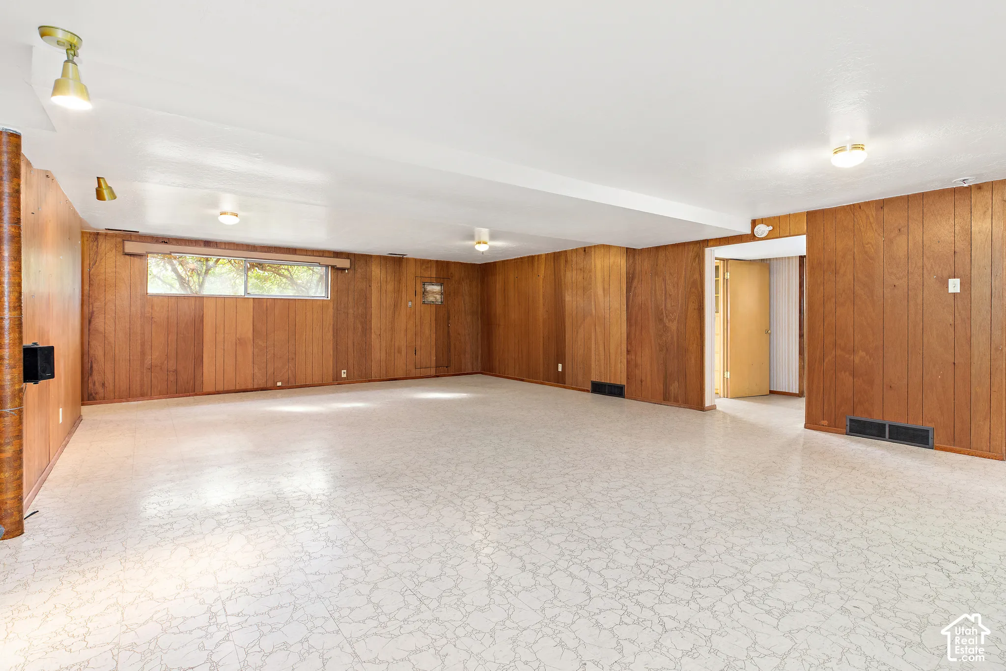 Open-concept room featuring vertical wood-finish wall paneling, light-toned patterned tile flooring, and multiple flush-mount ceiling light fixtures