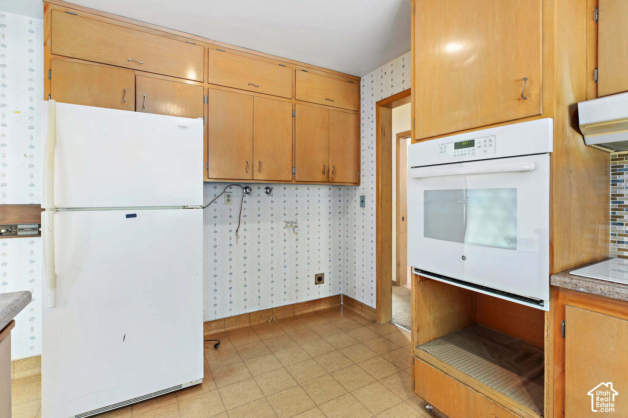 Kitchen featuring natural wood cabinetry, built-in wall oven, top-mount refrigerator, and square-tile flooring
