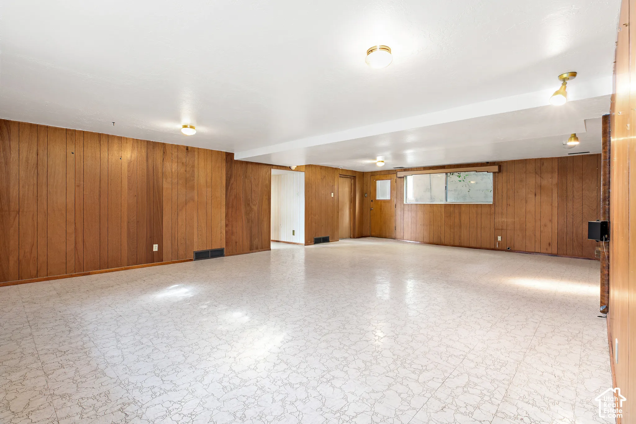 Interior space featuring wood-paneling wall finishes, patterned resilient flooring, and multiple ceiling-mounted light fixtures