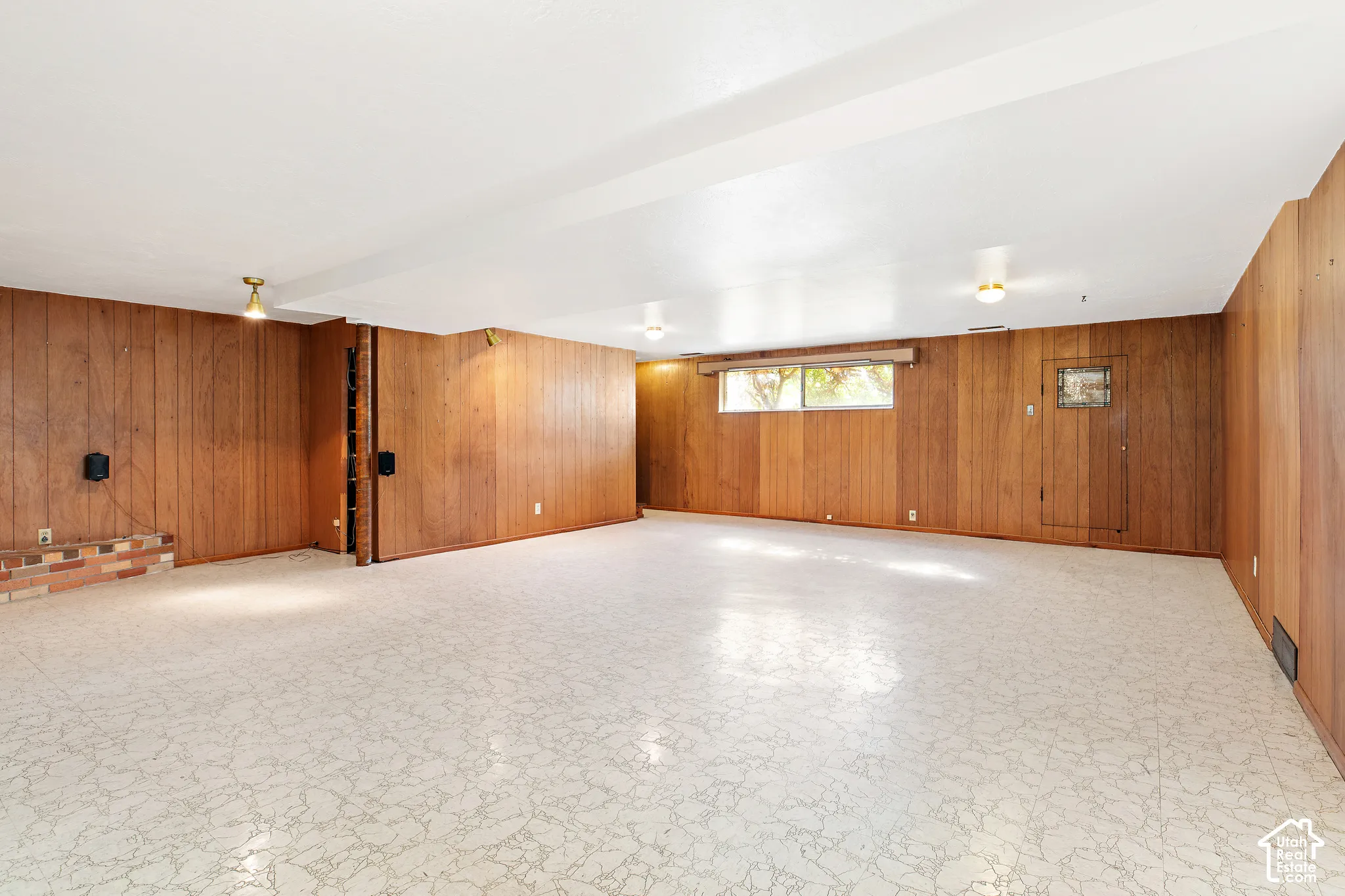 Wood-paneled walls, light-toned resilient flooring, brick hearth, and recessed ceiling lighting