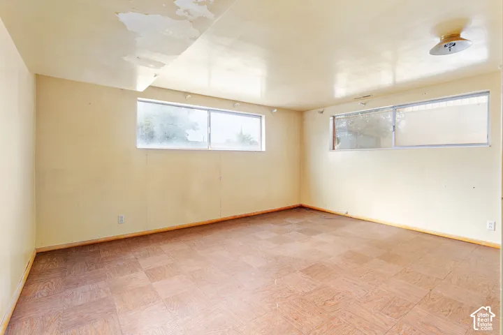 Room featuring wood-patterned parquet flooring, dual sliding windows, and a flush-mount ceiling light fixture
