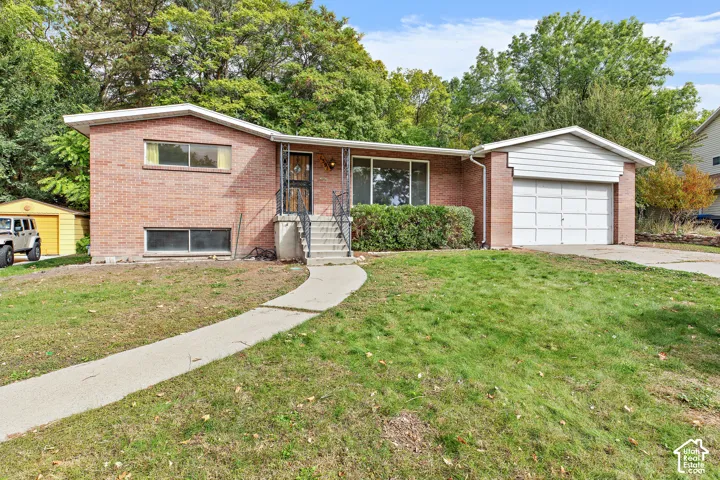 Brick exterior residence featuring a concrete walkway, single-car attached garage, and metal porch railing