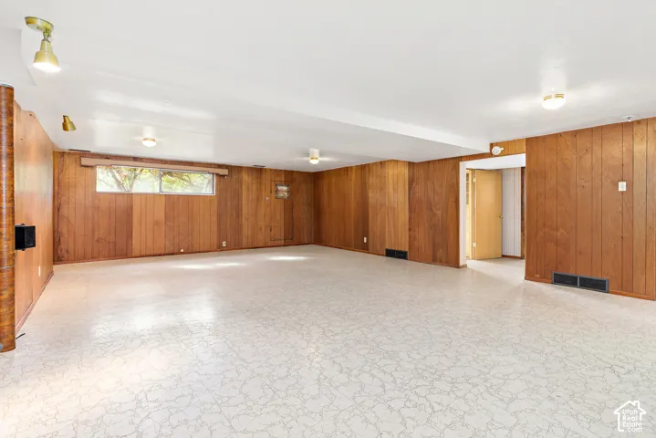 Open-concept room featuring vertical wood-finish wall paneling, light-toned patterned tile flooring, and multiple flush-mount ceiling light fixtures