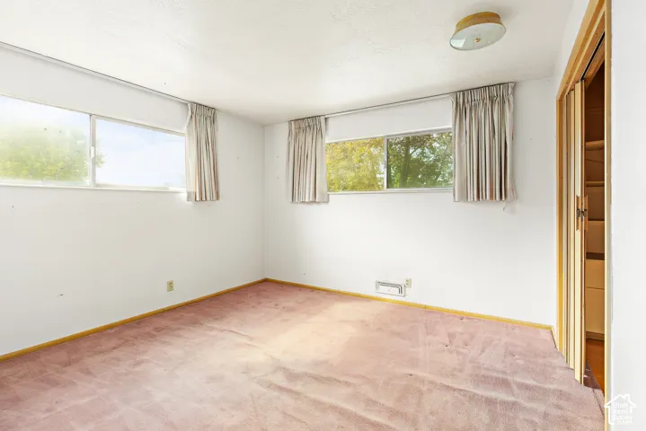 Interior room featuring two large horizontal sliding windows, carpeting, a ceiling-mounted light fixture, and wooden bifold closet doors