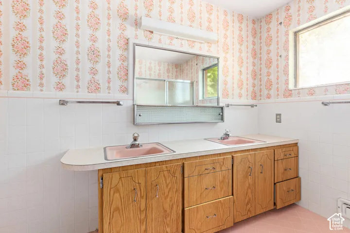 Dual-sink vanity featuring wood-finish cabinetry, integrated countertop, two drop-in sinks, and a wall-mounted medicine cabinet with mirror