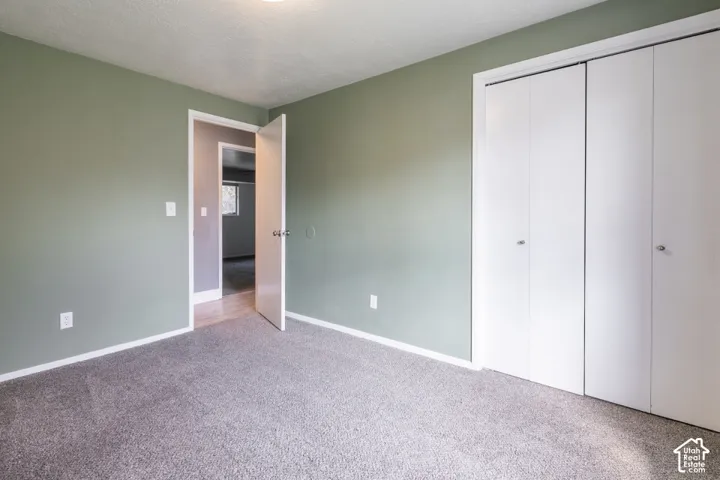 Bedroom #2 featuring neutral wall paint, carpeted flooring, and a double-door closet.