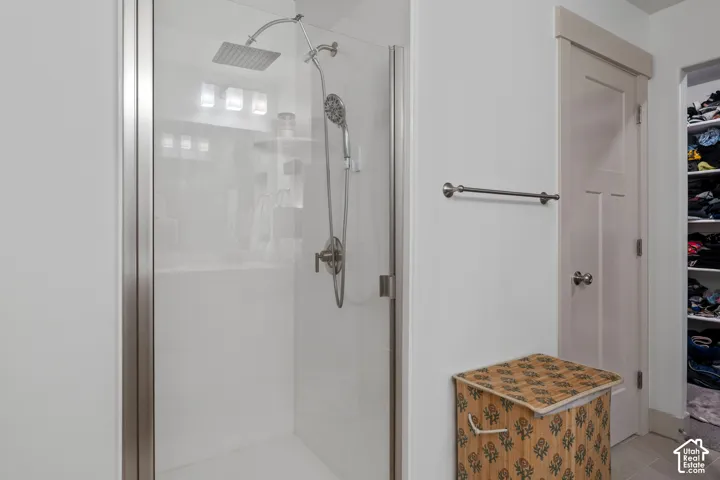 Walk-in shower featuring a glass enclosure, rainfall showerhead, and handheld sprayer attachment, complemented by a solid-core interior door