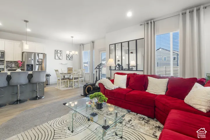 Open concept living area featuring light wood-finish flooring, white cabinetry, a kitchen island, recessed lighting, and a decorative black-framed glass partition