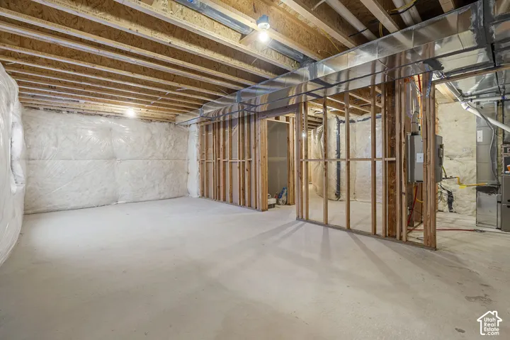 Unfinished basement featuring exposed wood-framing, concrete flooring, plastic-sheathed foundation walls, and exposed metal ductwork