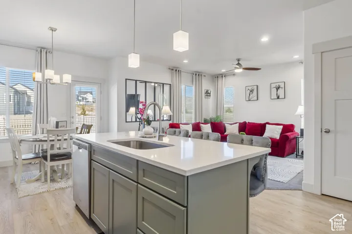 Kitchen featuring a center island with solid surface countertop, stainless steel undermount sink, shaker-style cabinetry, and pendant lighting
