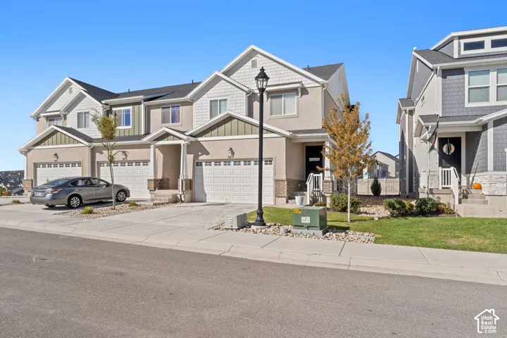 Multi-family residence exterior featuring a mix of stucco and shaker-style siding, stone veneer accents, multi-pane windows, and attached two-car garages
