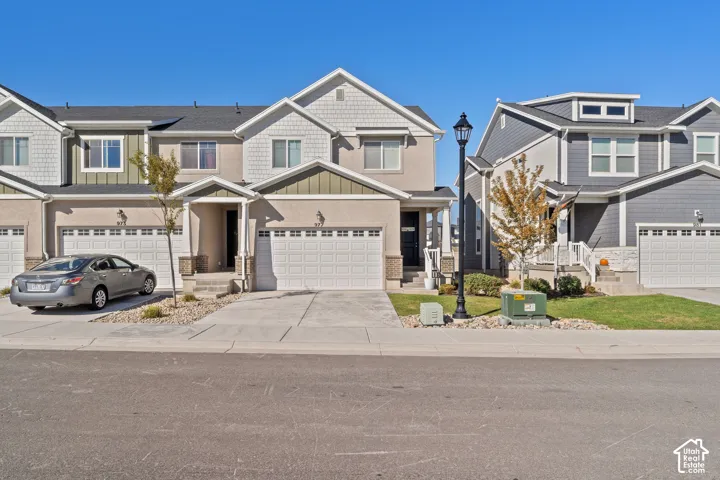 Multi-level residential exterior featuring stucco and shake siding, an attached two-car garage, and concrete driveway