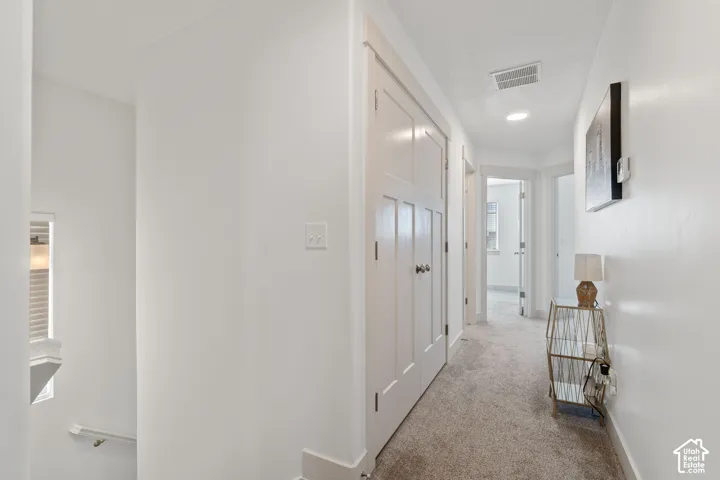 Hallway featuring wall-to-wall carpeting, shaker-style double doors, recessed lighting, and white door casings
