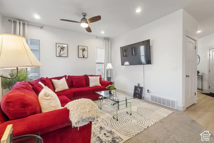 Living area featuring recessed lighting, a modern ceiling fan, wood-finish flooring, and a multi-panel door