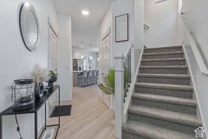 Entryway featuring wood-finish flooring, a carpeted staircase with a white balustrade, recessed ceiling lighting, and multi-panel interior doors