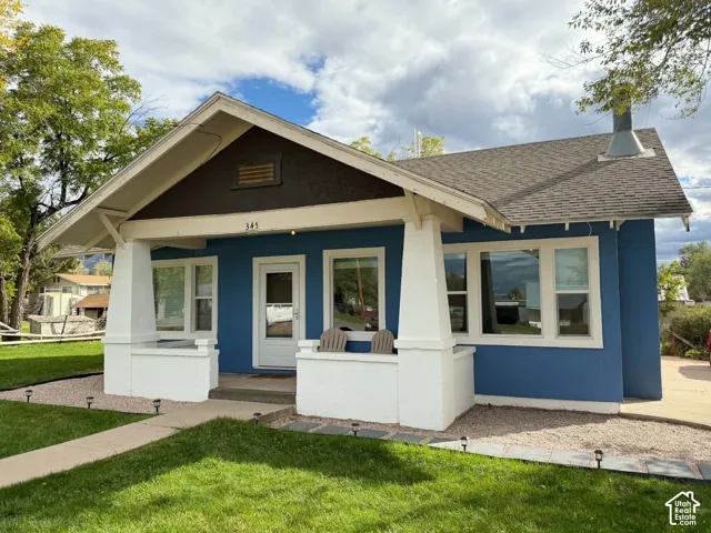 Bungalow-style exterior featuring tapered porch columns, a gabled roofline, contrast stucco siding, and a covered front porch