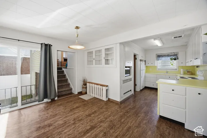 Kitchen area featuring white cabinetry, wood-finish flooring, built-in display shelving, and glass sliding doors