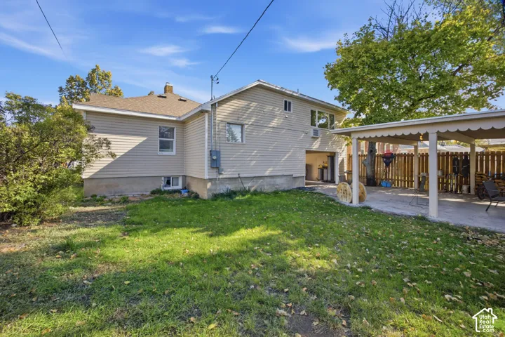 Rear exterior featuring horizontal vinyl siding, a covered patio with decorative scalloped trim, a concrete foundation, and a wood-slat perimeter fence