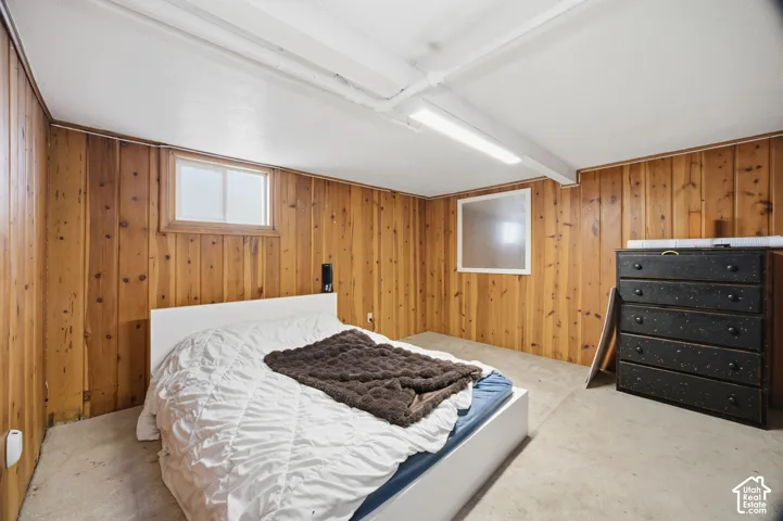 Finished room featuring wood-paneled walls, neutral carpeting, and linear overhead lighting