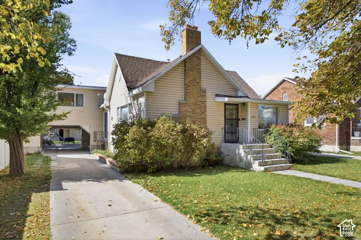 Vinyl siding exterior featuring a brick chimney, concrete driveway, and an attached carport