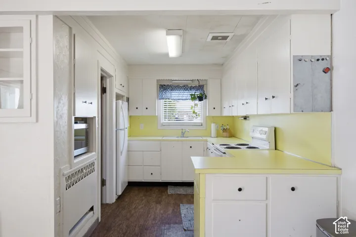 Kitchen featuring white cabinetry, solid-surface countertops, built-in wall oven, and wood-finish flooring