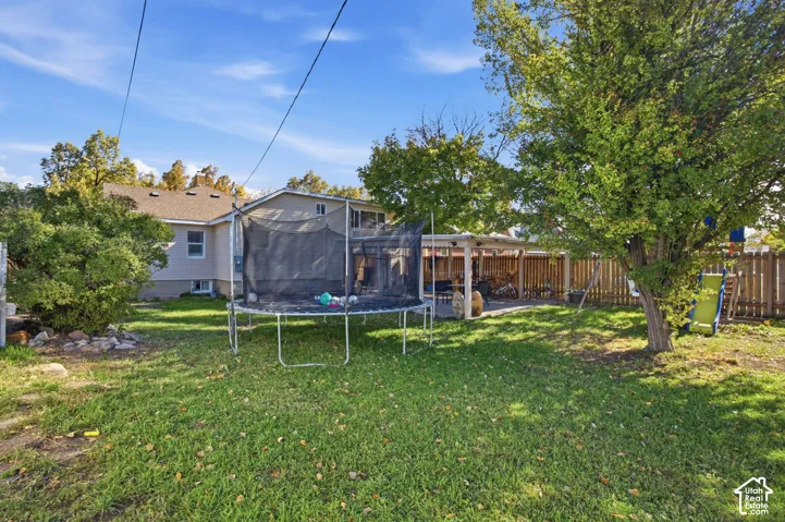 Backyard featuring a covered patio, wood-style privacy fencing, and mature trees