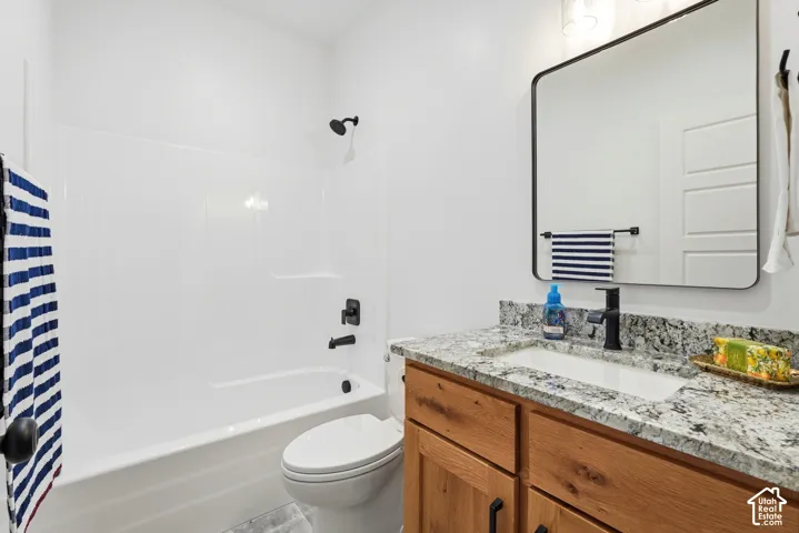 Bathroom featuring a wood-finish vanity with a stone-composite countertop, undermount sink, matte black faucet, and a wall-mounted rectangular mirror with a black frame