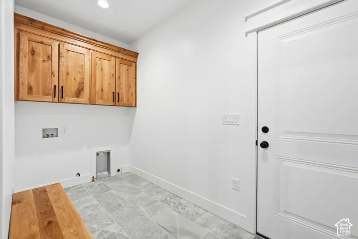 Custom wood-finish upper cabinetry with matte black hardware, grey stone-finish tile flooring, and a solid-core panel door