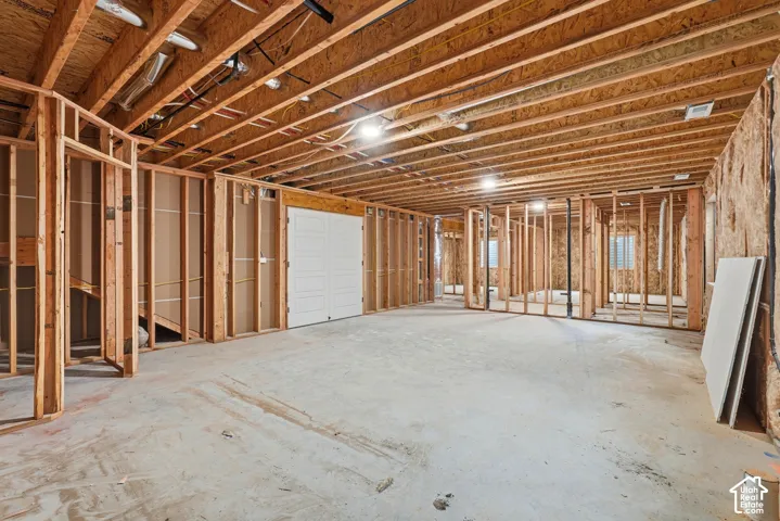 Unfinished basement level featuring exposed wood framing, concrete flooring, and double doors