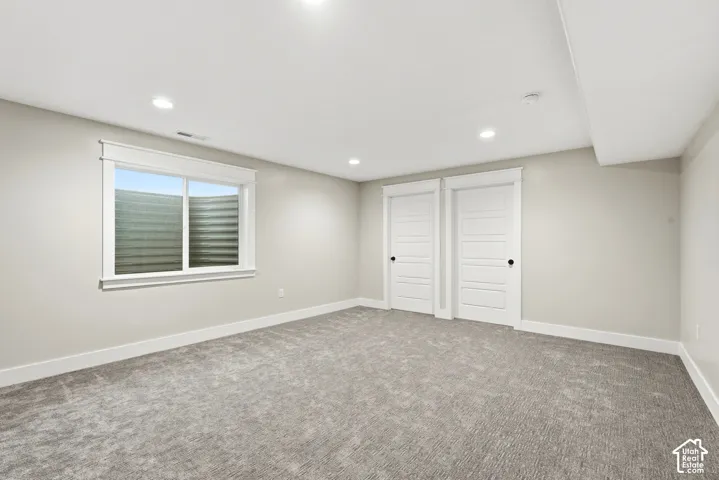 Neutral wall tones, recessed lighting, wall-to-wall carpeting, window with egress well, and dual interior doors with flat-panel detailing