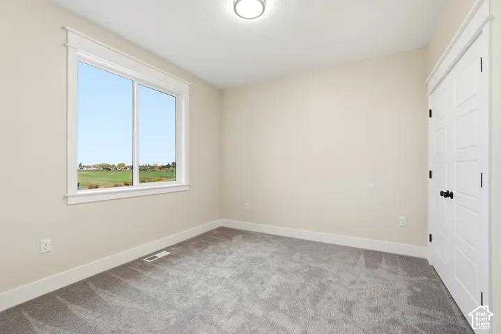 Neutral wall tones, gray carpeting, dual-pane window with exterior landscape, and white paneled doors with black hardware