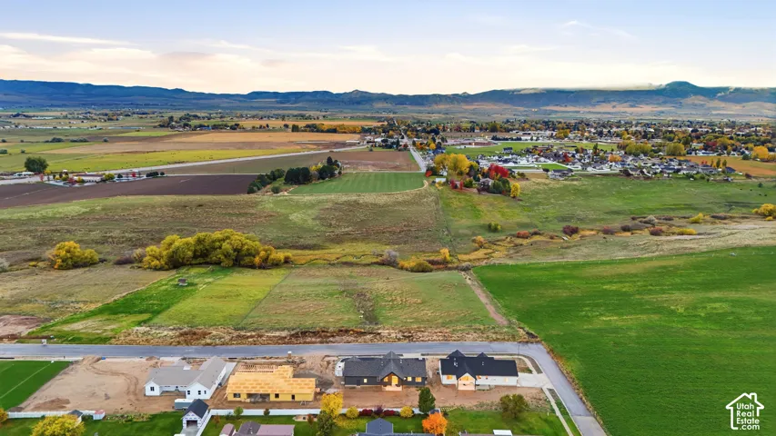 Aerial perspective of expansive open land with mountain backdrop and established rural acreage