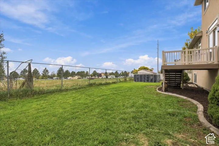 Rear yard featuring an elevated composite deck with stairs, chain-link fencing, and defined landscape edging