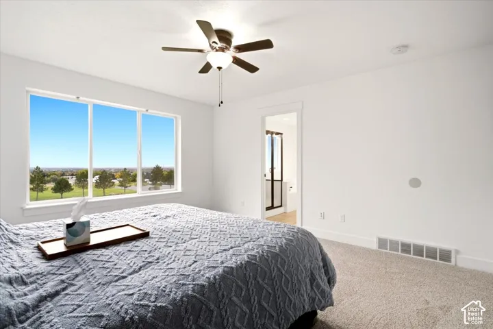 Large window with expansive exterior scenery, ceiling fan with integrated lighting, neutral wall paint, and carpeted flooring