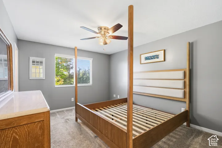 Neutral-toned room featuring wall-to-wall carpeting, a multi-blade ceiling fan with integrated lighting, and a single-pane horizontal window