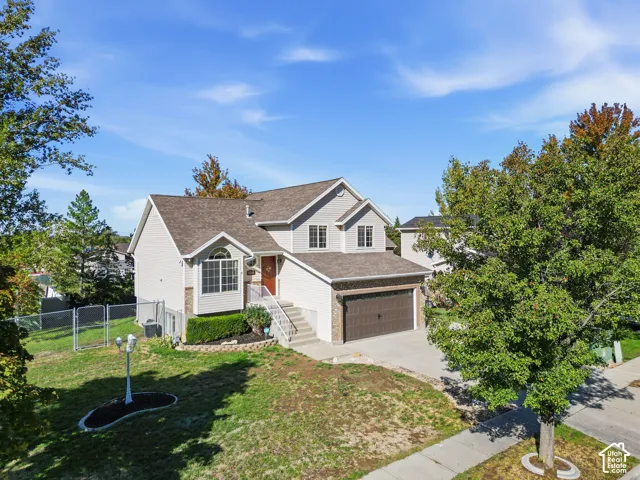 Two-story residence featuring horizontal lap siding, stone veneer accents, a multi-gabled roofline, an attached two-car garage, and a concrete driveway